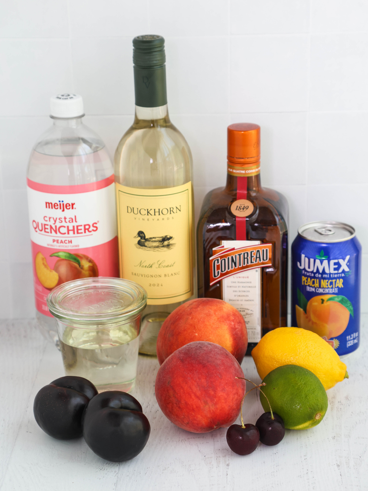 Ingredients for white peach sangria on a white background.