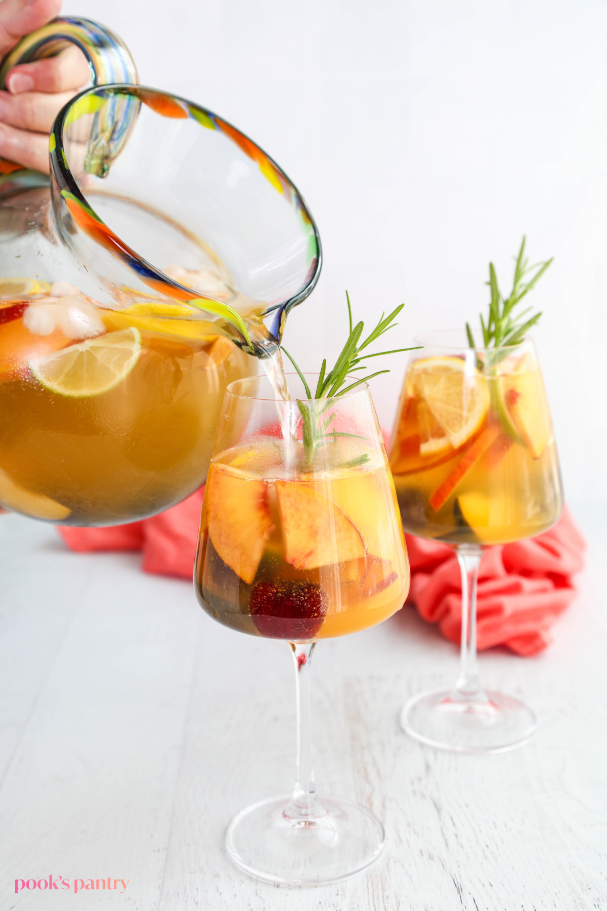 Pouring a glass of white sangria with fresh fruit.