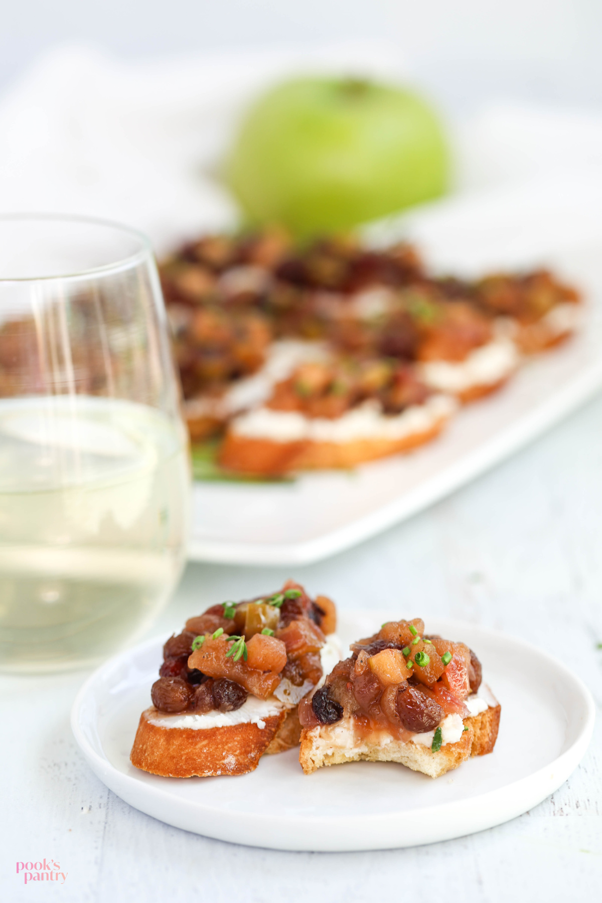 Pieces of crostini on a small white plate, with a bite taken out of one of the pieces.