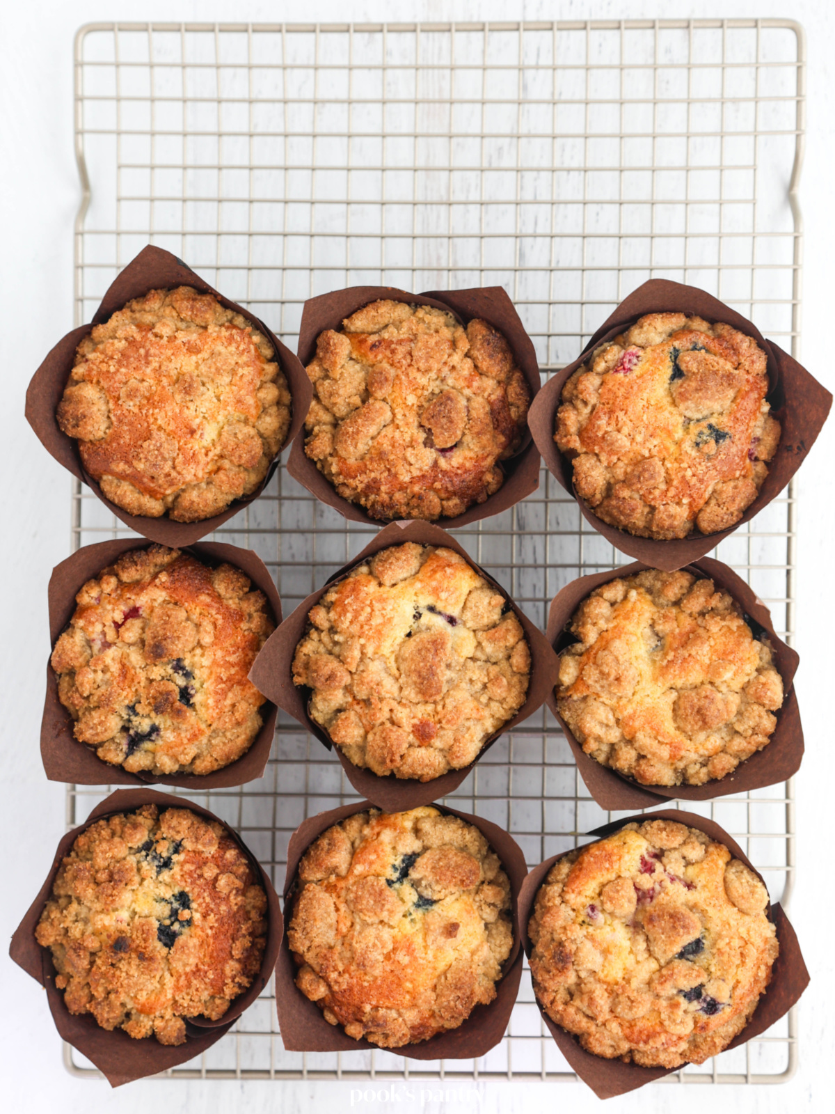 Baked mixed berry muffins on a cooling rack.