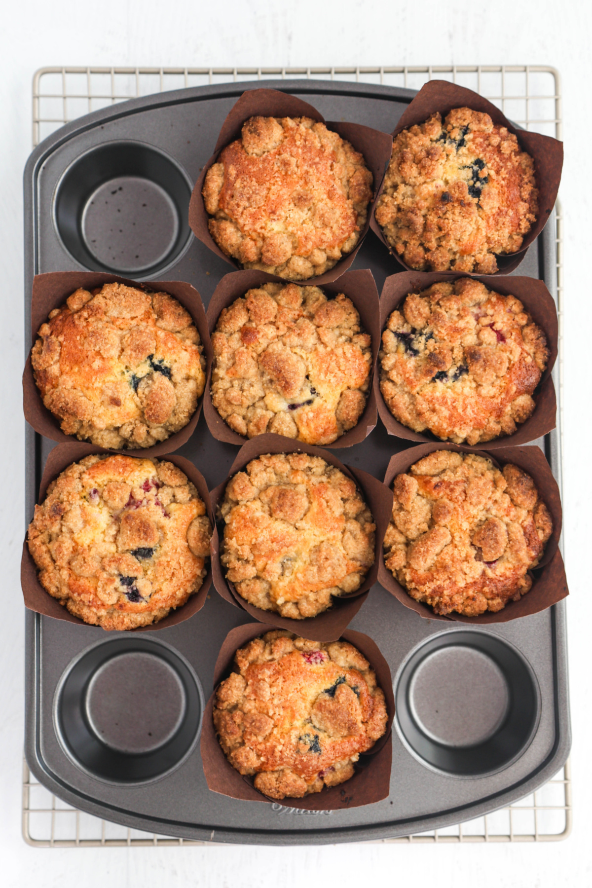 Freshly baked muffins in the baking tin, showing the crumb topping.