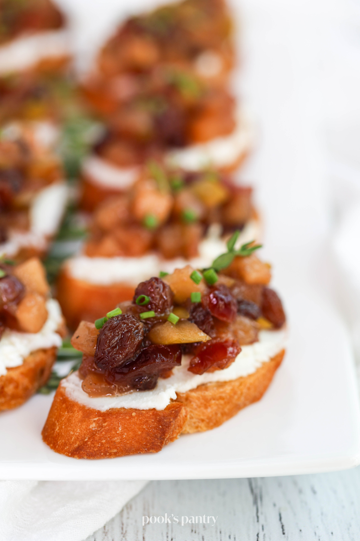 Close up photo of apple chutney with goat cheese on toasted bread, on a platter.