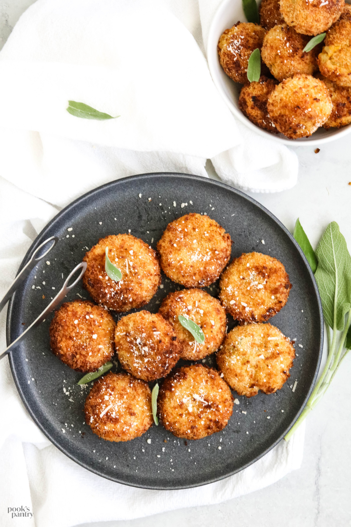 Butternut squash risotto cakes on a charcoal gray plate, sprinkled with Parmesan cheese.