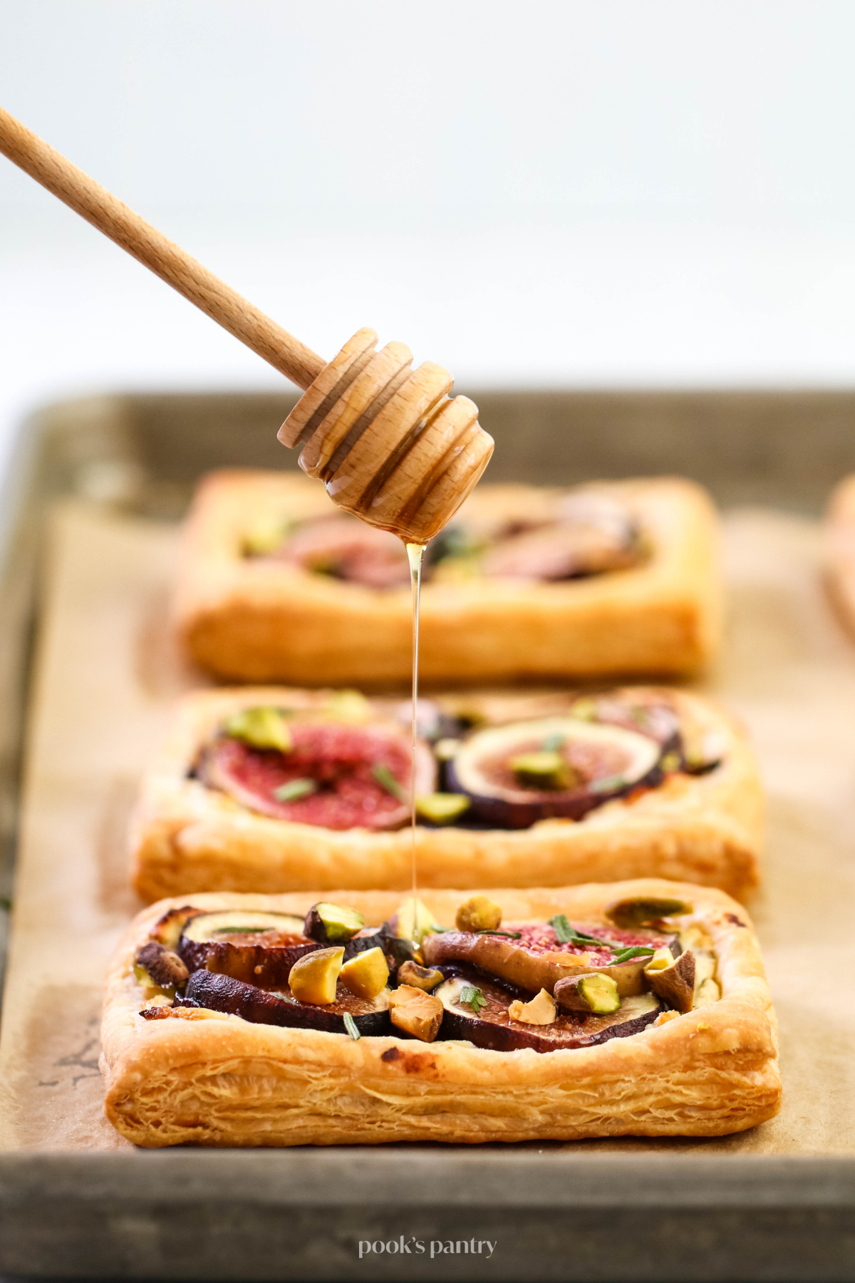 Drizzling honey on savory fig puff pastry tarts.