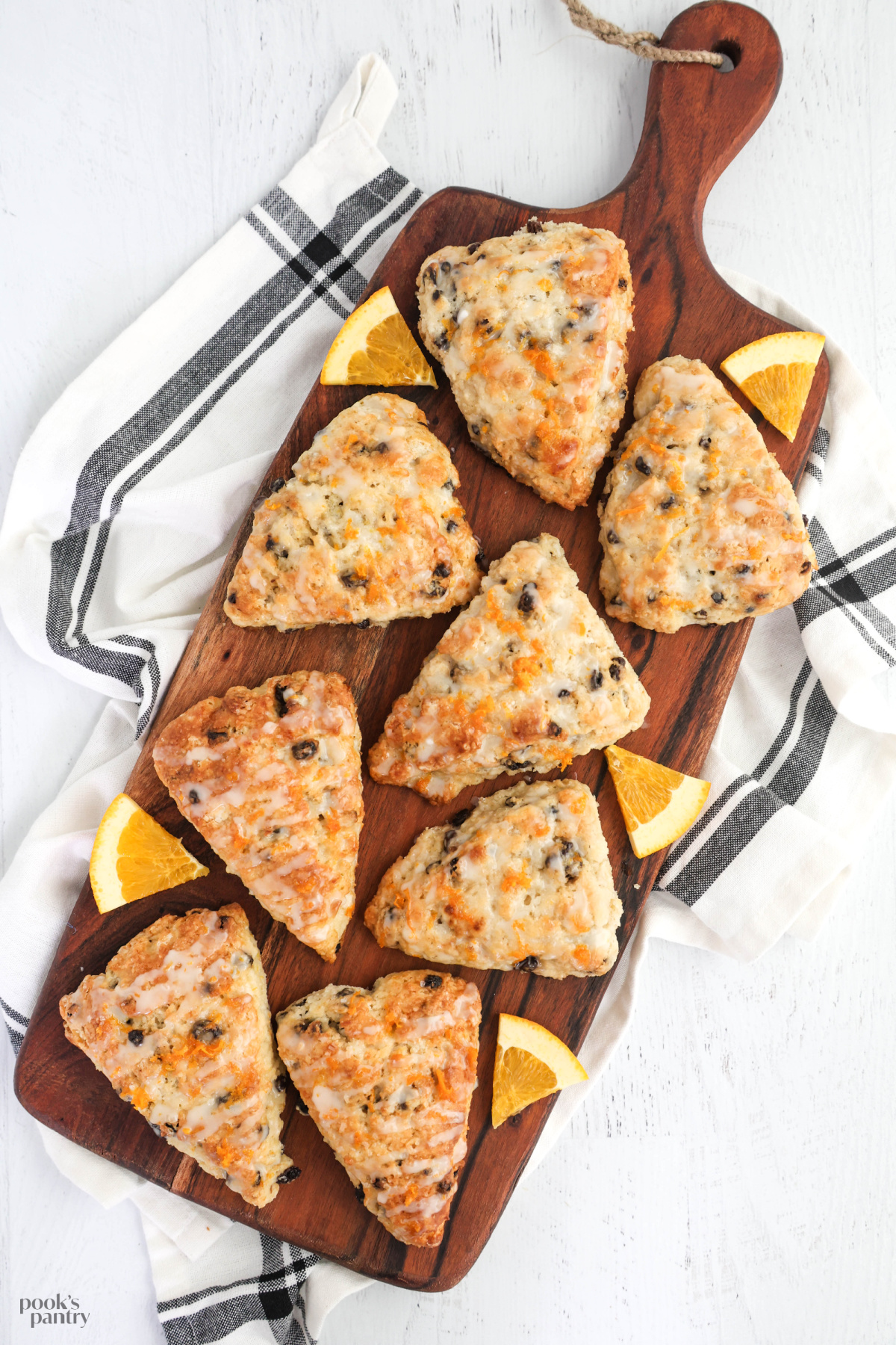 Overhead photo of scones arranged on a brown wooden board on a white background.