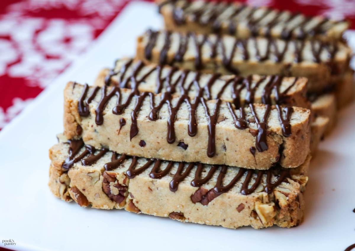 Biscotti drizzled with chocolate on a white platter.