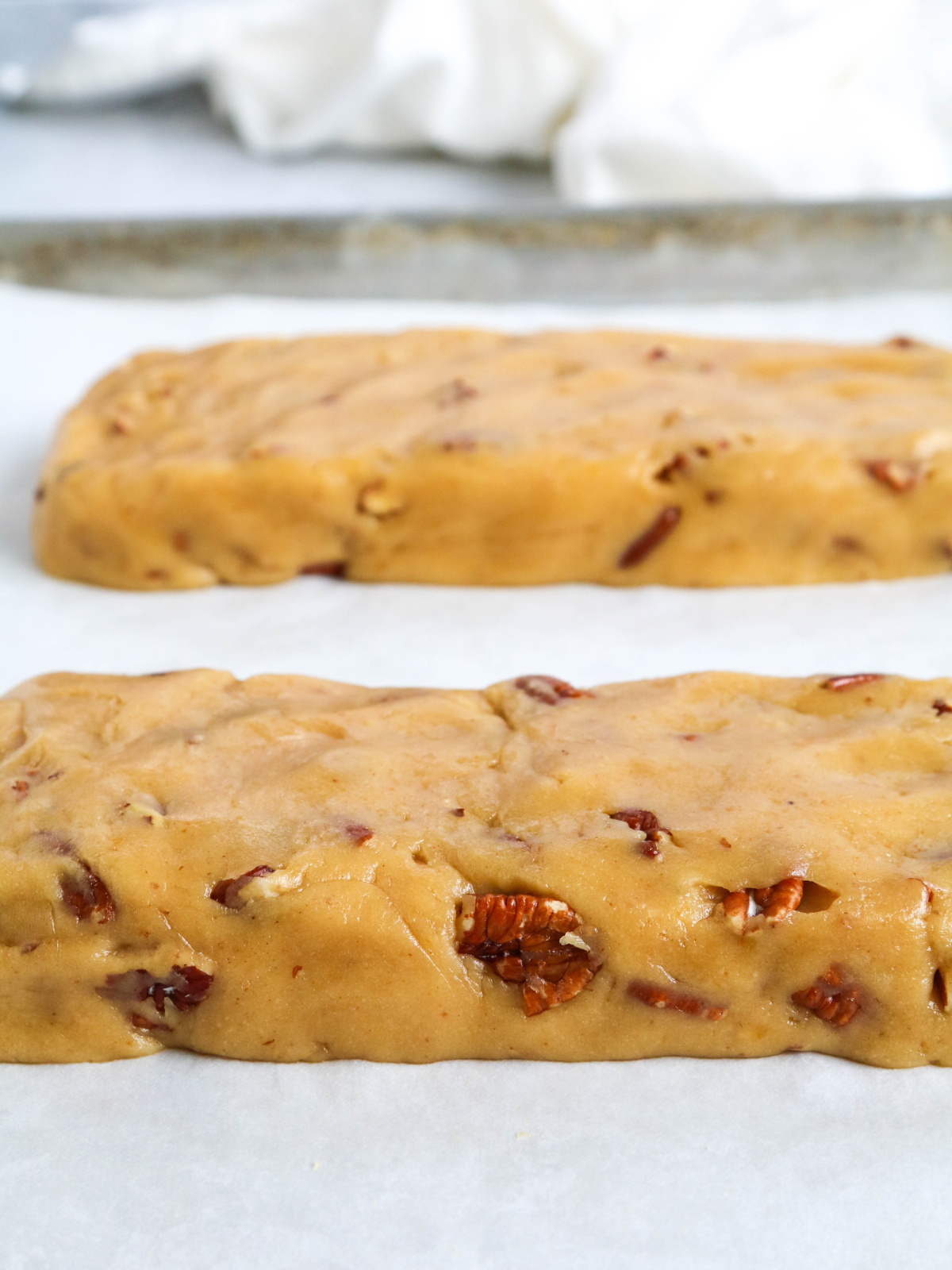 Two logs of biscotti dough on a lined sheet pan, ready for the oven.