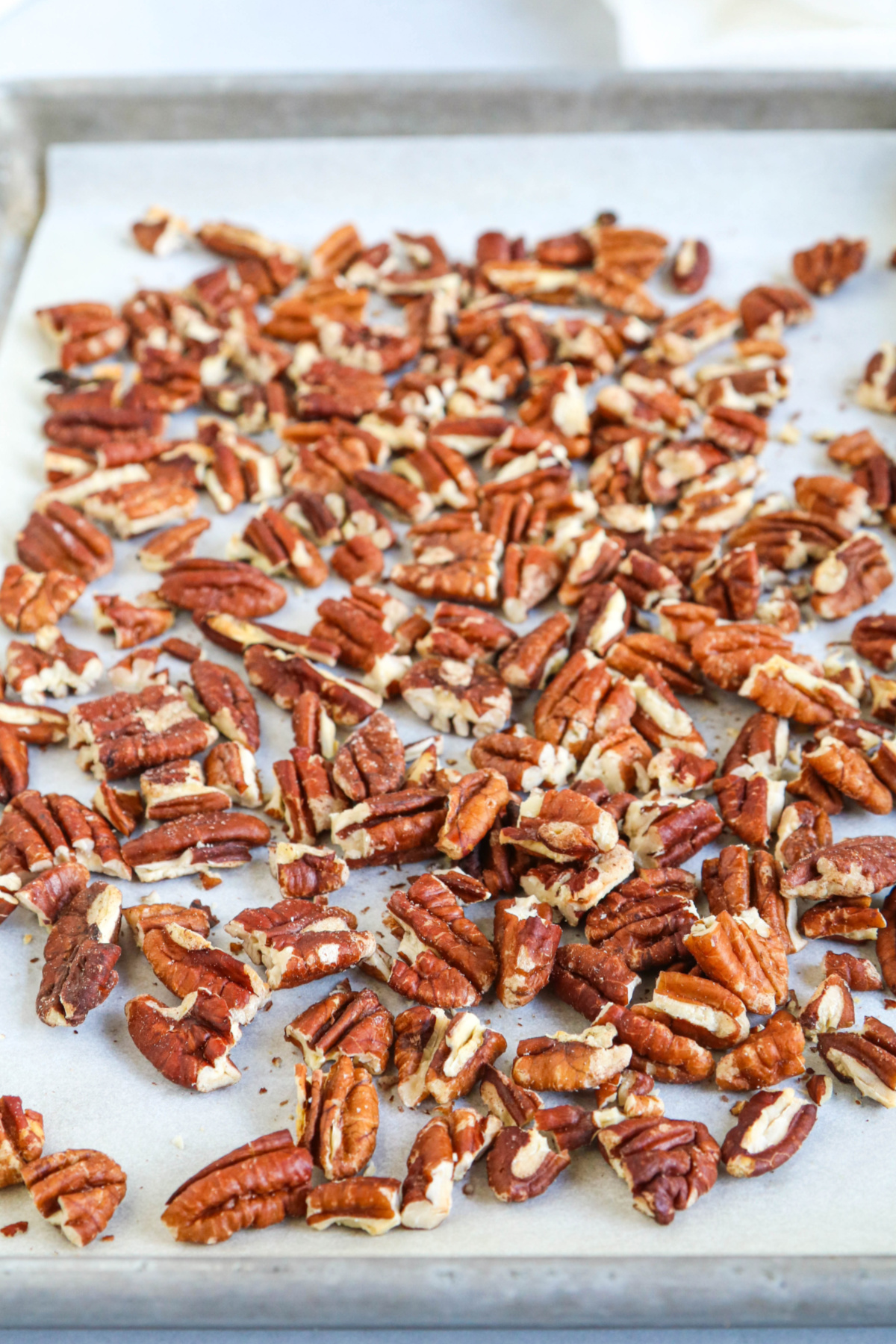 Toasted pecans on a parchment-lined baking sheet.