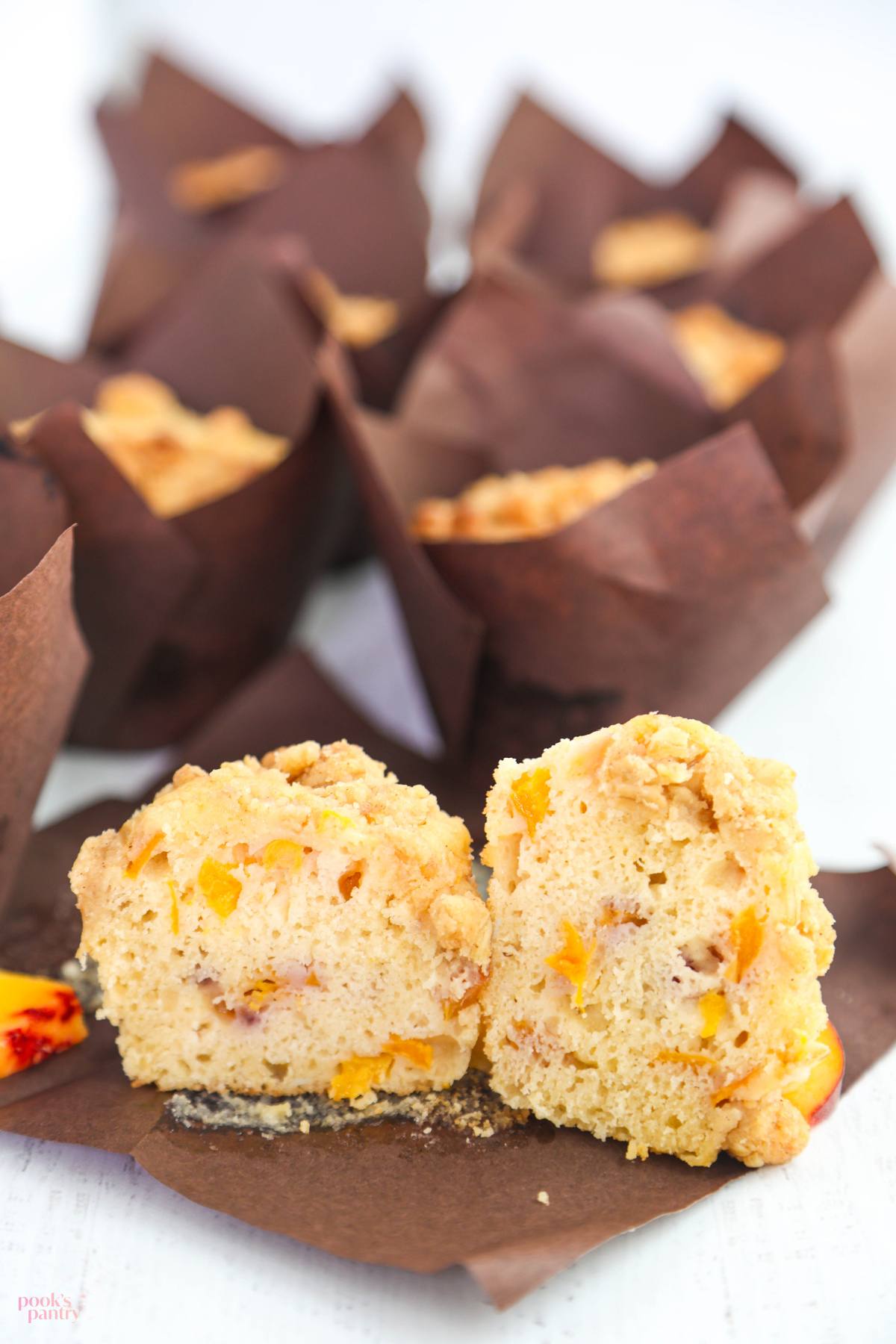 Cut open muffins showing that the muffins are packed with evenly distributed peaches throughout.