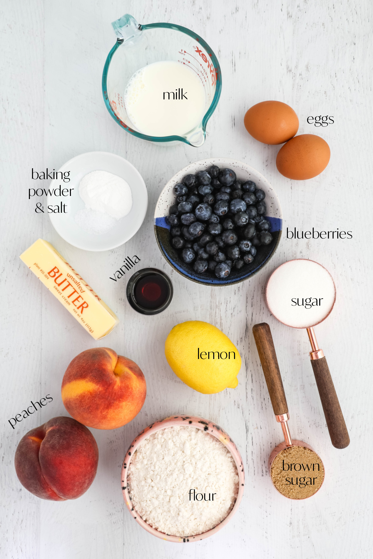 Ingredients for blueberry peach muffins on a light gray background.